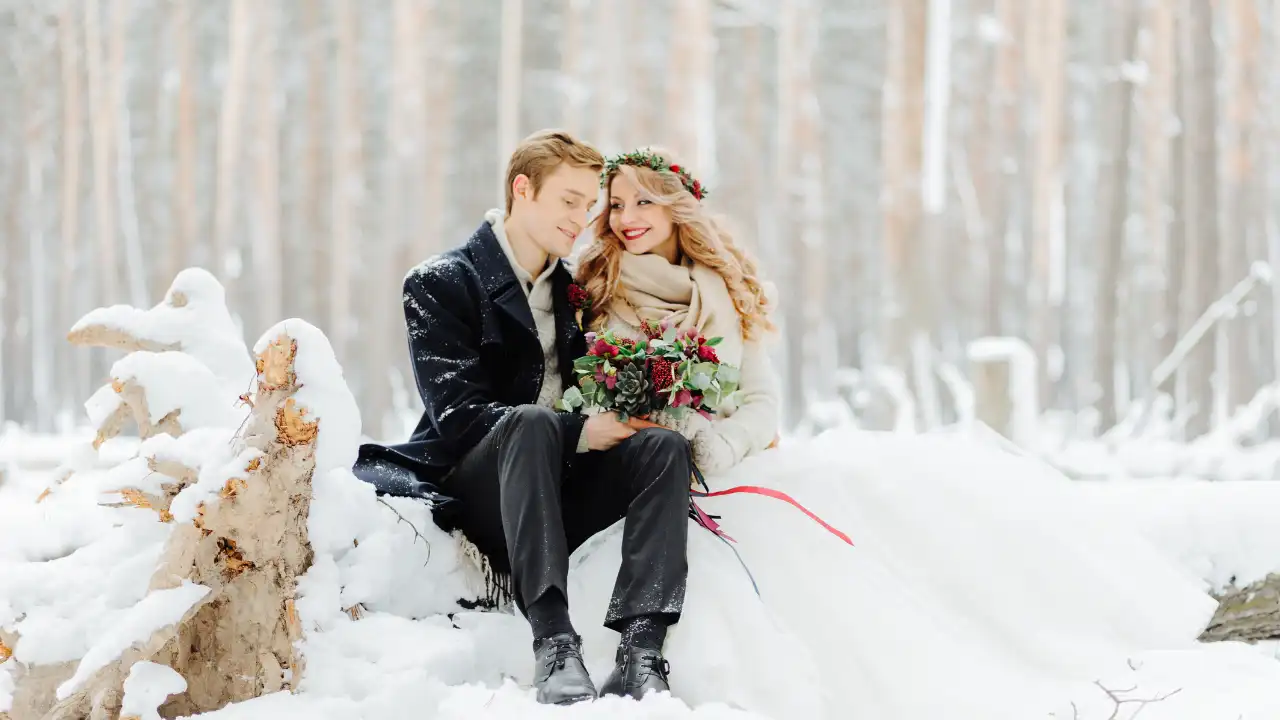 Nevěsta a ženich sedící v zasněžené krajině umělecká fotografie