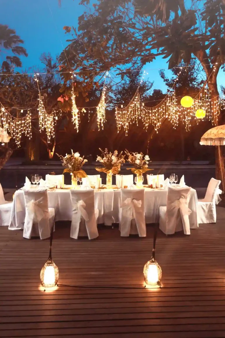 Slavnostně připravený a nazdobený stůl a židle v bílém provedení na svatbu a dekorace.